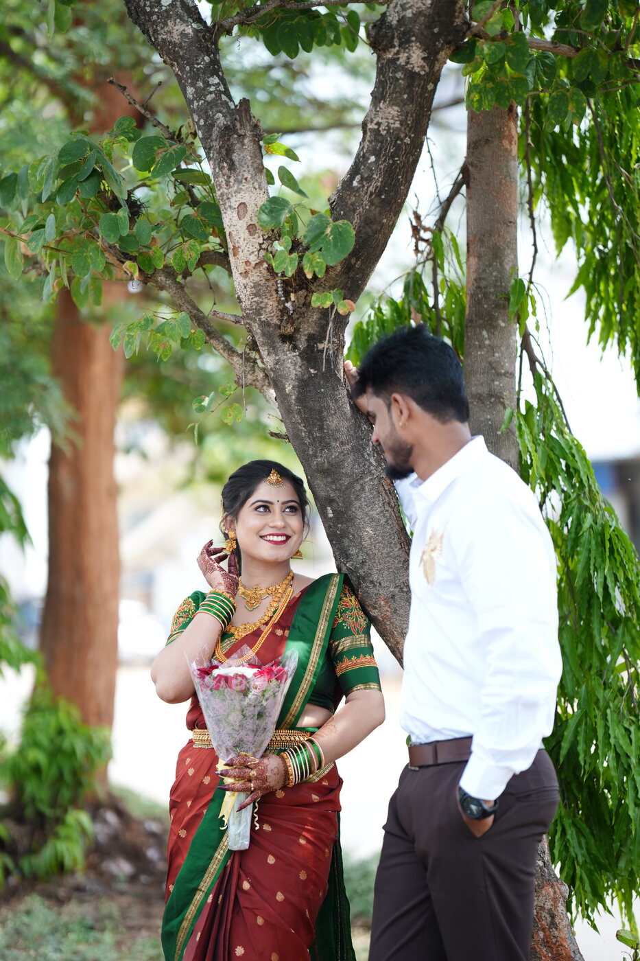 Bhoomika in a maroon and green silk saree holding flowers, Sanjay beside her