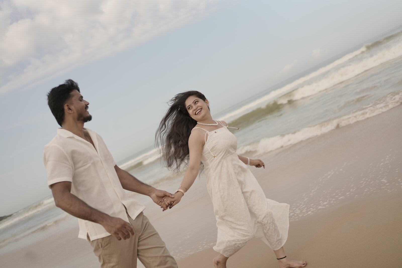 Bhoomika and Sanjay walking hand in hand along the shoreline